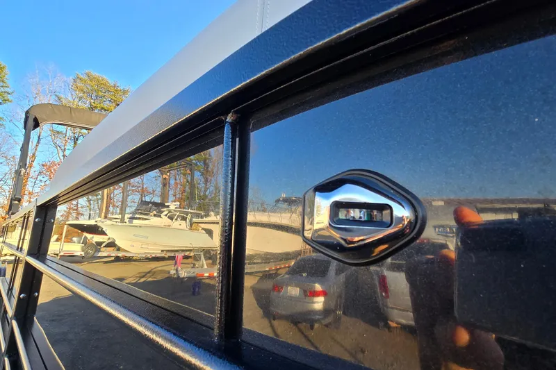 Slide: The Image of 2023 Veranda Vista View 20RC boat detail with chrome accent, reflecting nearby boats and trees. - 12