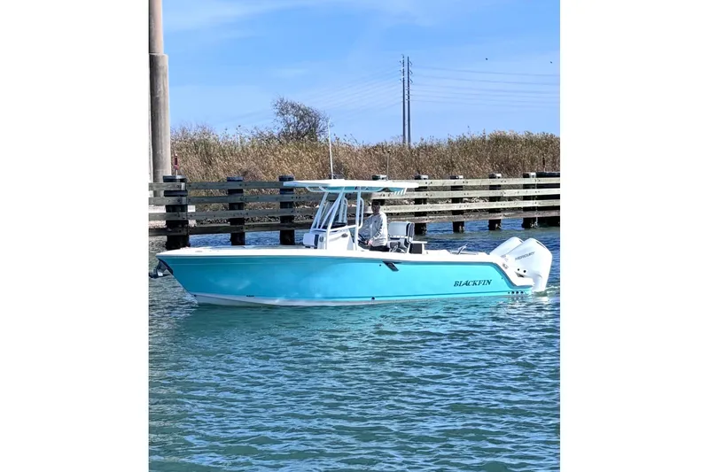 The Image of 2021 Blackfin 252 CC boat in blue, cruising near a wooden dock. - 1