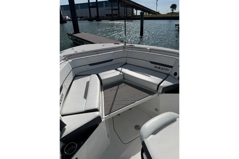 Slide: The Image of 2021 Blackfin 252 CC boat interior with cushioned seating and dock view. - 10