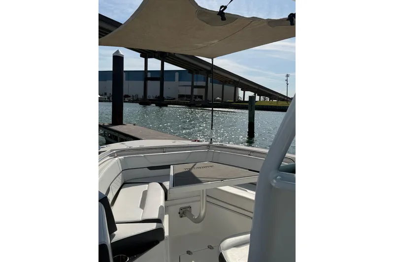 Slide: The Image of 2021 Blackfin 252 CC boat docked, featuring shaded seating and waterfront view. - 6