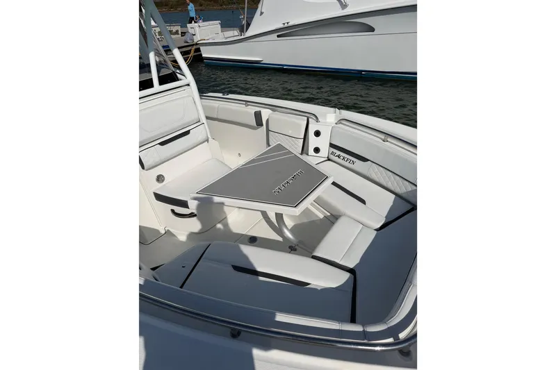 Slide: The Image of 2021 Blackfin 252 CC boat interior with seating and table, docked by the water. - 9