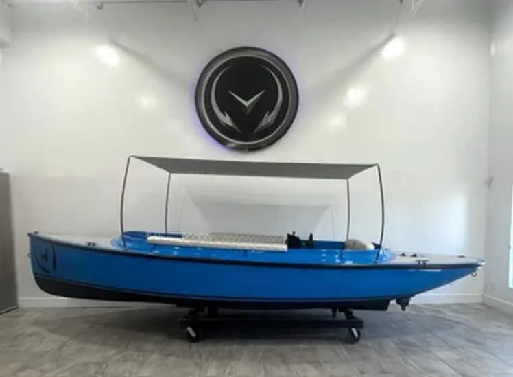Slide: The Image of 2024 Vision Marine Technologies Fantail 217 electric boat in showroom, blue with canopy. - 5
