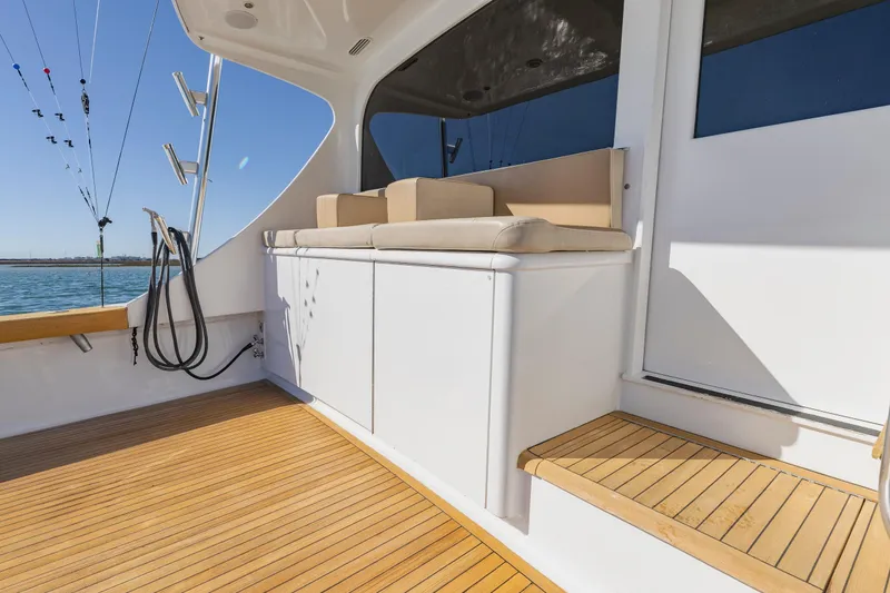 Slide: The Image of Luxury Weaver 61 yacht deck with cushioned seating, wooden flooring, and fishing rods, 2005 model. - 48