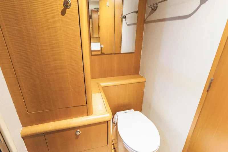 Slide: The Image of Wooden bathroom interior on a 2005 Weaver 61 yacht, featuring a toilet and mirror. - 63