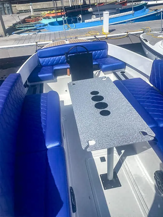 Slide: The Image of 2023 Vision Marine Technologies Fantail 217 boat with blue seating and central table at dock. - 7