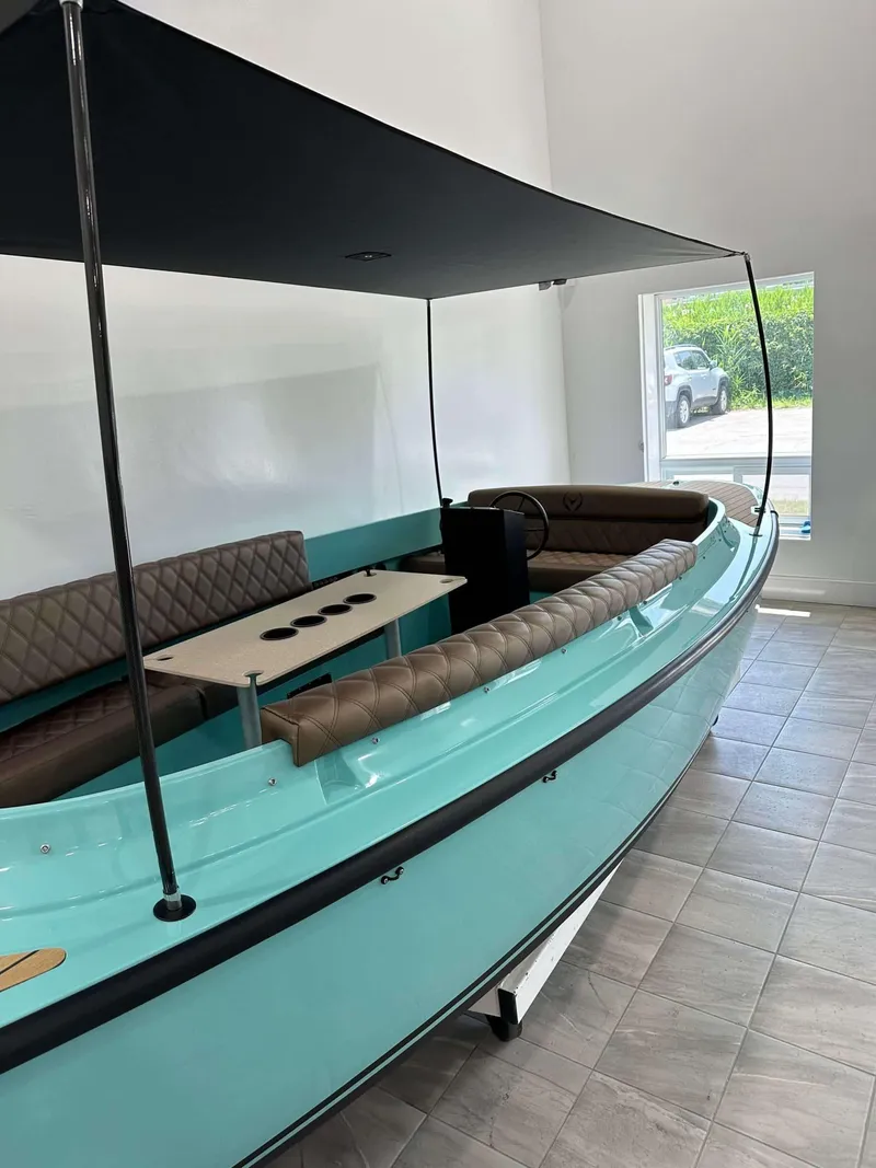 Slide: The Image of 2023 Vision Marine Technologies Fantail 217 boat with canopy and seating, displayed indoors. - 1