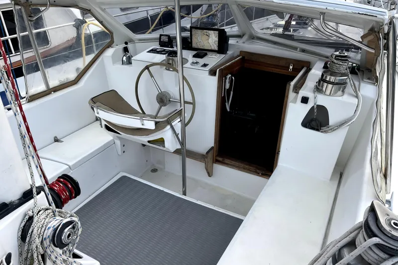 Slide: The Image of 1979 Amel Mango sailboat cockpit with steering wheel, navigation equipment, and winches. - 16