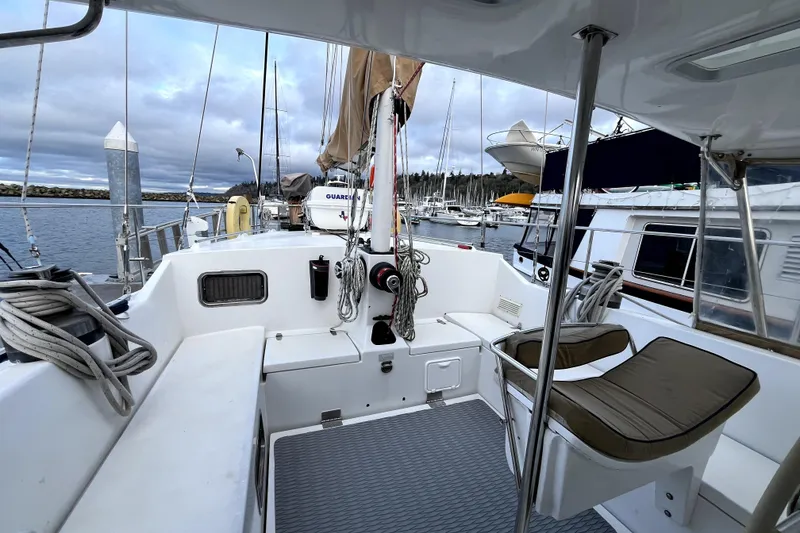 Slide: The Image of 1979 Amel Mango sailboat cockpit with seating, docked in a marina under cloudy skies. - 17