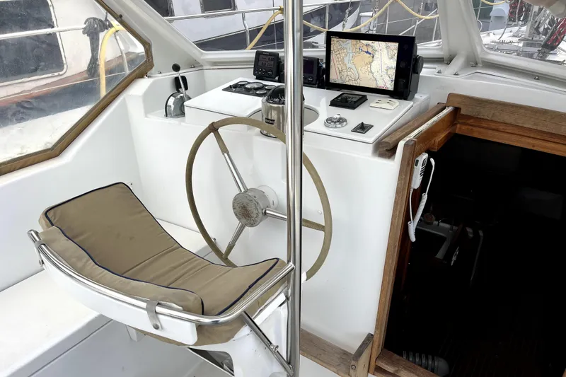 Slide: The Image of 1979 Amel Mango yacht cockpit with steering wheel, navigation equipment, and cushioned seat. - 18