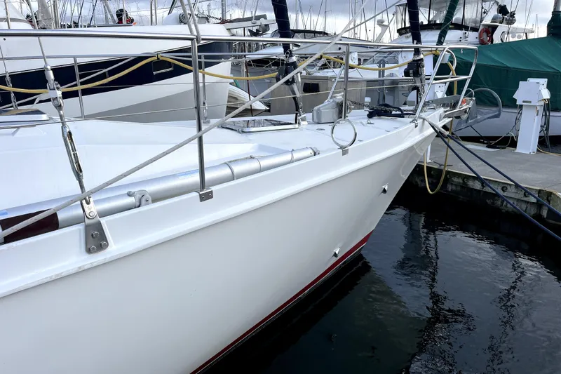 Slide: The Image of 1979 Amel Mango sailboat docked at a marina, featuring sleek white hull and metal railings. - 9