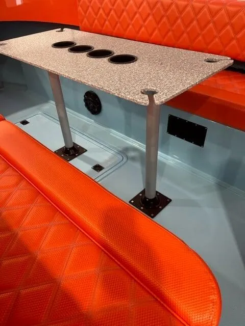 Slide: The Image of 2023 Vision Marine Fantail 217 interior with orange seating and speckled table featuring cup holders. - 1