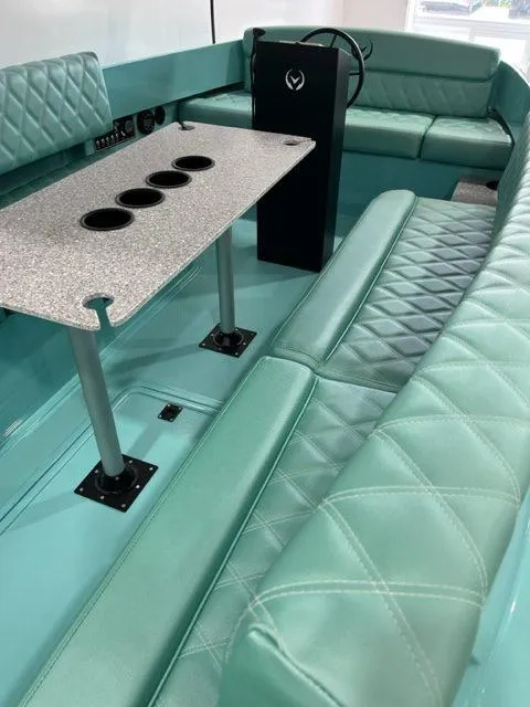 Slide: The Image of 2023 Vision Marine Technologies Fantail 217 interior with teal seating and a table with cup holders. - 2