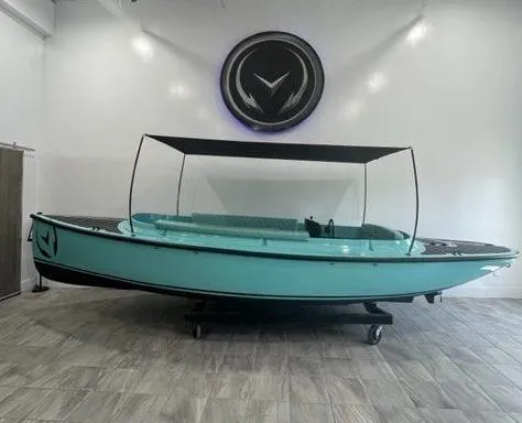 Slide: The Image of 2023 Vision Marine Technologies Fantail 217 electric boat in showroom, turquoise with black canopy. - 5