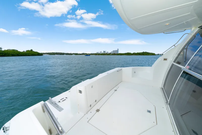 Slide: The Image of 2001 Cruisers Yachts 5000 Sedan Sport on serene water with city skyline view. - 15