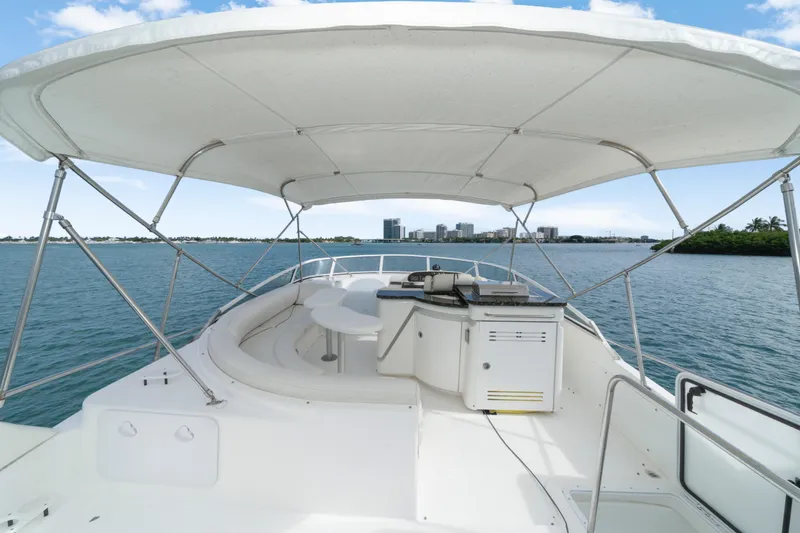 Slide: The Image of 2001 Cruisers Yachts 5000 Sedan Sport with canopy, overlooking serene waters and distant cityscape. - 31