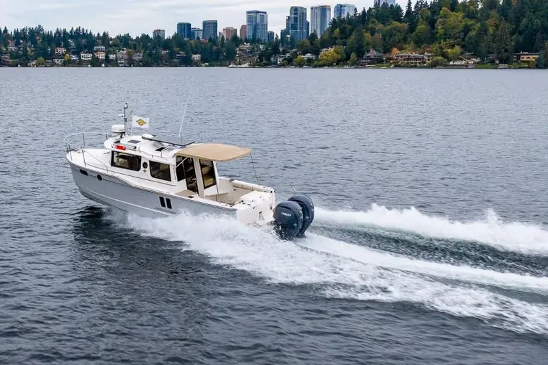 The Image of 2026 Ranger Tugs R-27 cruising on a lake with city skyline in background. - 0