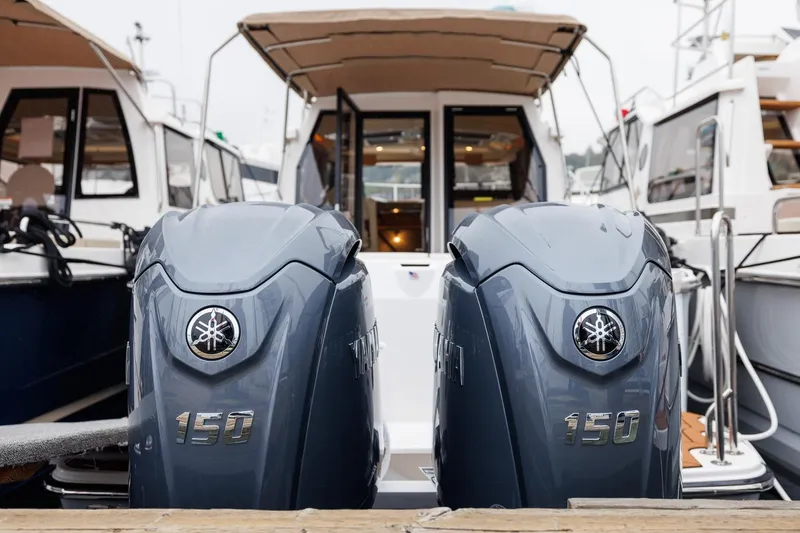 Slide: The Image of 2026 Ranger Tugs R-27 with dual Yamaha 150 outboard engines at a marina. - 2