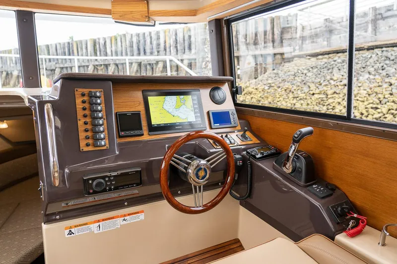 Slide: The Image of Manufacturer Provided Image: 2025 Ranger Tugs R-27 helm with navigation system and wooden steering wheel. - 9