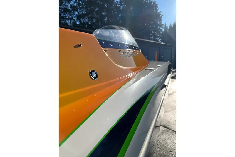 Slide: The Image of 2007 Eliminator Daytona 30 boat with vibrant orange and green detailing, side view. - 16
