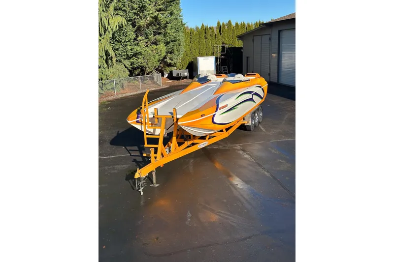 Slide: The Image of 2007 Eliminator Daytona 30 speedboat on trailer, vibrant orange and white design, parked outdoors. - 26