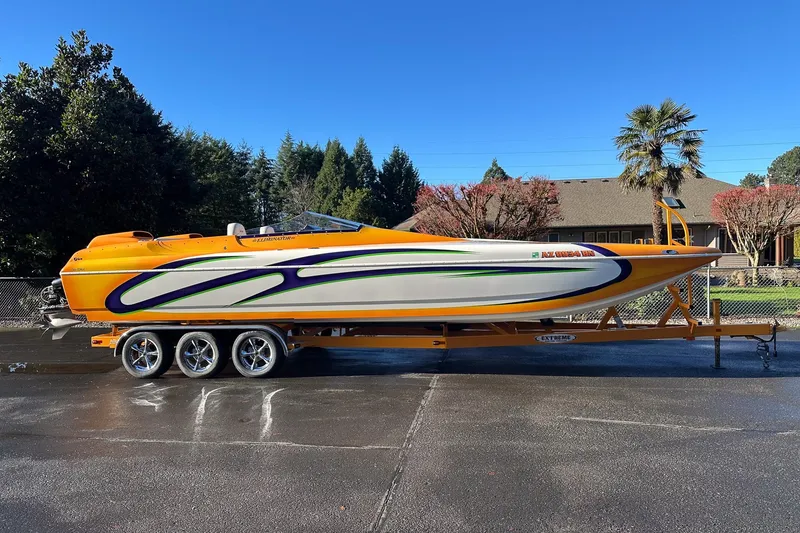 Slide: The Image of 2007 Eliminator Daytona 30 speedboat on trailer, vibrant orange and white design, parked outdoors. - 38