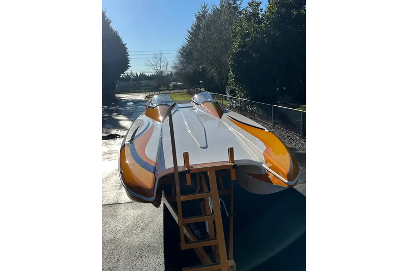 Slide: The Image of 2007 Eliminator Daytona 30 powerboat with vibrant orange and white design, parked outdoors. - 43