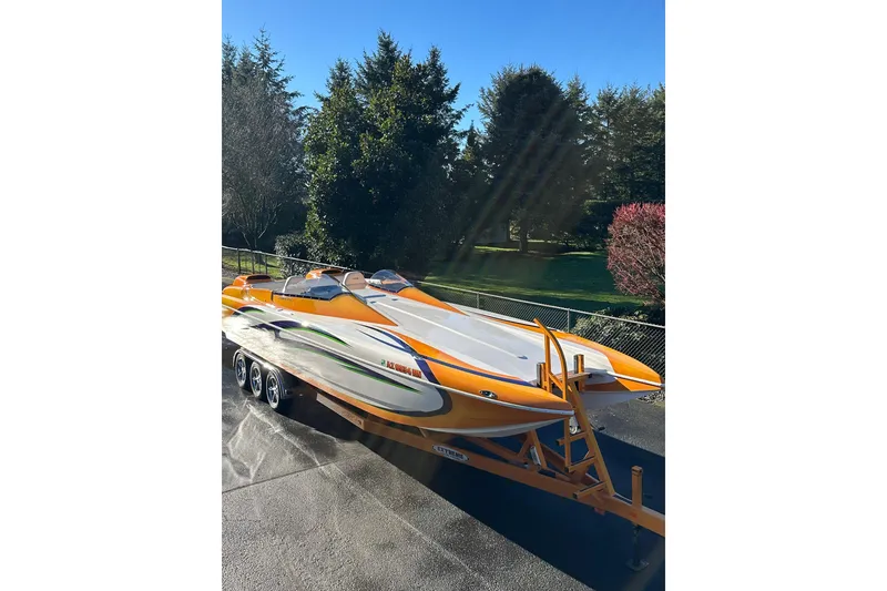 Slide: The Image of 2007 Eliminator Daytona 30 speedboat on trailer, vibrant orange and white design, parked outdoors. - 45