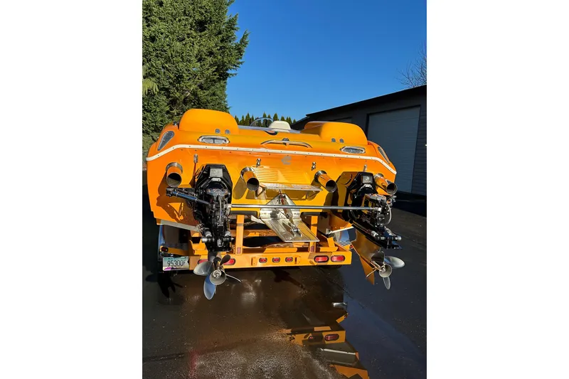 Slide: The Image of 2007 Eliminator Daytona 30 boat, vibrant orange, dual engines, parked outdoors. - 48