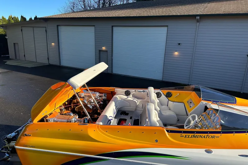 Slide: The Image of 2007 Eliminator Daytona 30 speedboat with vibrant orange and white interior, parked near a garage. - 50