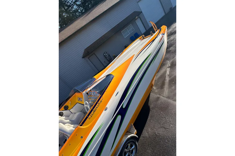 Slide: The Image of 2007 Eliminator Daytona 30 boat with vibrant orange and green accents, parked outdoors. - 51