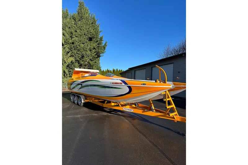 Slide: The Image of 2007 Eliminator Daytona 30 speedboat on trailer, vibrant orange and white design, parked outdoors. - 52