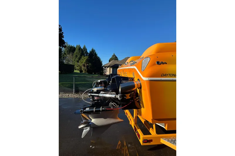 Slide: The Image of 2007 Eliminator Daytona 30 boat with vibrant orange exterior and powerful engine, parked outdoors. - 9