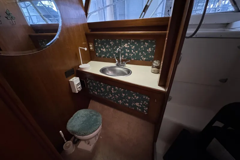 Slide: The Image of 1967 Pacemaker 37 boat bathroom with sink, floral wallpaper, and teal toilet cover. - 11