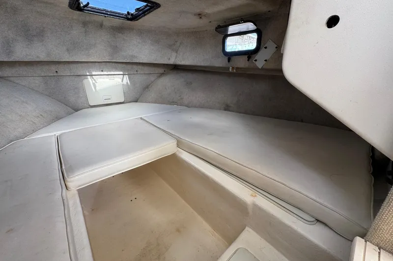 Slide: The Image of Interior cabin of a 2001 Parker 2110 Walkaround boat, featuring cushioned seating and small windows. - 21