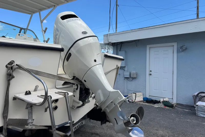Slide: The Image of 2001 Parker 2110 Walkaround boat with outboard motor, docked near a blue building. - 27
