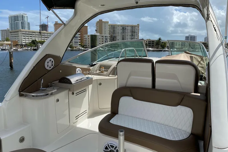 Slide: The Image of 2008 Sea Ray 310 Sundancer interior with seating and kitchenette, docked in urban marina. - 12