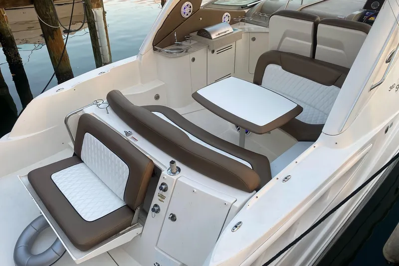 Slide: The Image of 2008 Sea Ray 310 Sundancer boat interior with seating and table, docked by the water. - 15