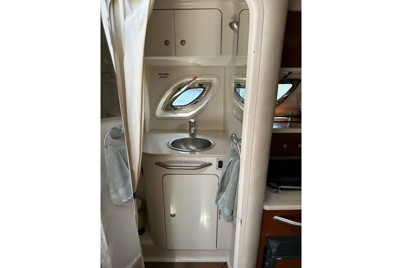 Slide: The Image of 2008 Sea Ray 310 Sundancer bathroom interior with sink and porthole windows. - 30