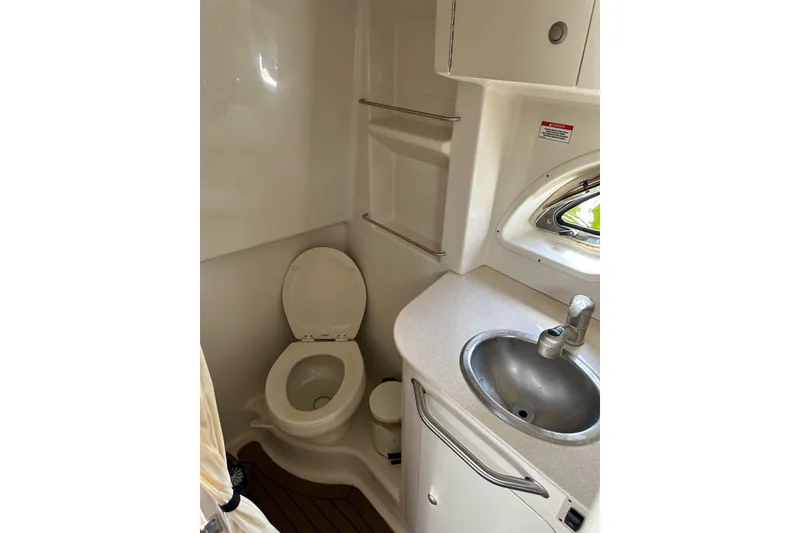 Slide: The Image of 2008 Sea Ray 310 Sundancer bathroom with toilet, sink, and porthole window. - 31