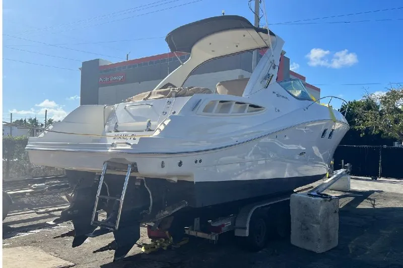 Slide: The Image of 2008 Sea Ray 310 Sundancer boat on trailer, parked outdoors under clear sky. - 32