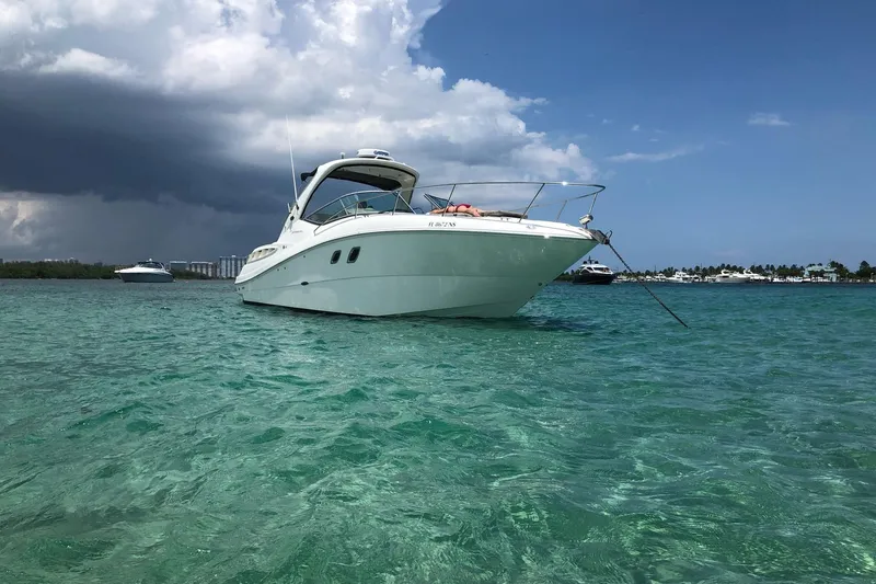 Slide: The Image of 2008 Sea Ray 310 Sundancer anchored in clear turquoise waters under a partly cloudy sky. - 6