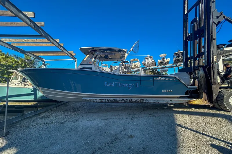 The Image of 2021 Grady-White Freedom 325 boat on forklift, blue hull, clear sky background. - 0