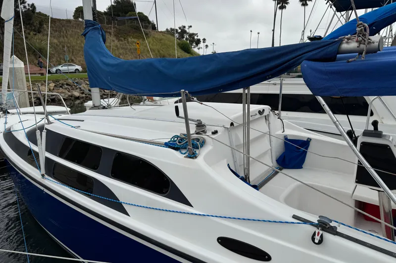Slide: The Image of 2005 MacGregor 26M Powersailer docked, featuring blue sail cover and sleek design. - 5