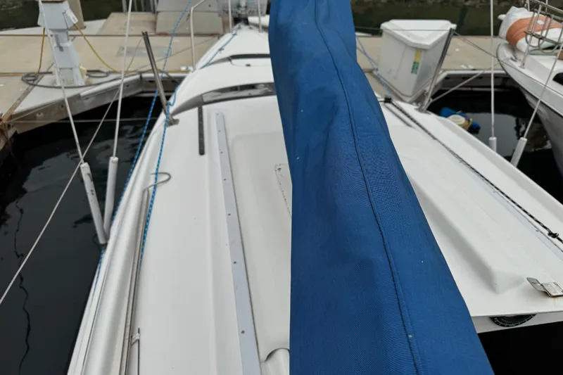 Slide: The Image of 2005 MacGregor 26M Powersailer docked, featuring blue sail cover and white deck. - 11