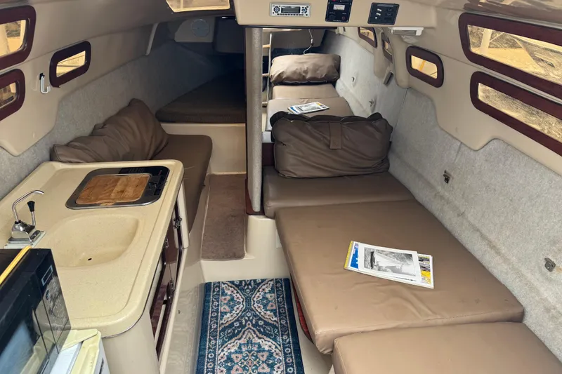 Slide: The Image of 2005 MacGregor 26M Powersailer interior with kitchenette, seating, and cozy cabin layout. - 19