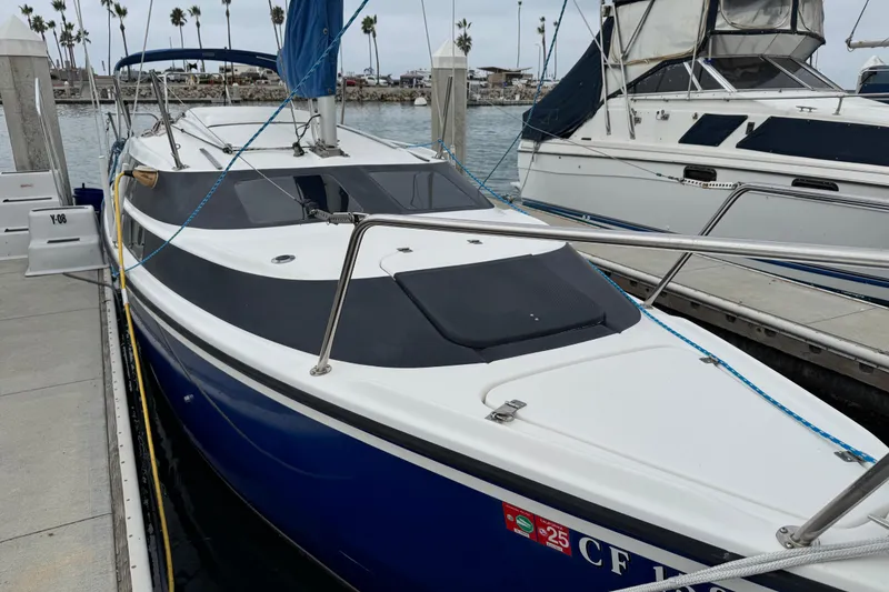 Slide: The Image of 2005 MacGregor 26M Powersailer docked at marina, featuring sleek blue and white design. - 2