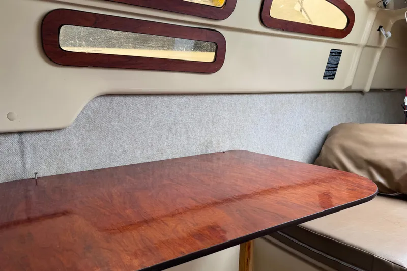 Slide: The Image of Interior of 2005 MacGregor 26M Powersailer with wooden table and cushioned seating. - 24