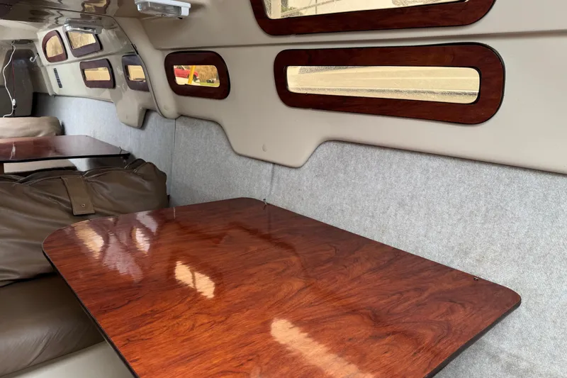 Slide: The Image of Interior of 2005 MacGregor 26M Powersailer with polished wood table and cushioned seating. - 25