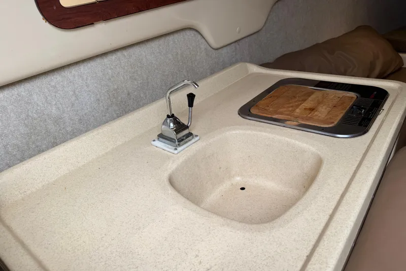 Slide: The Image of 2005 MacGregor 26M Powersailer interior sink and stove area with faucet and cutting board. - 27
