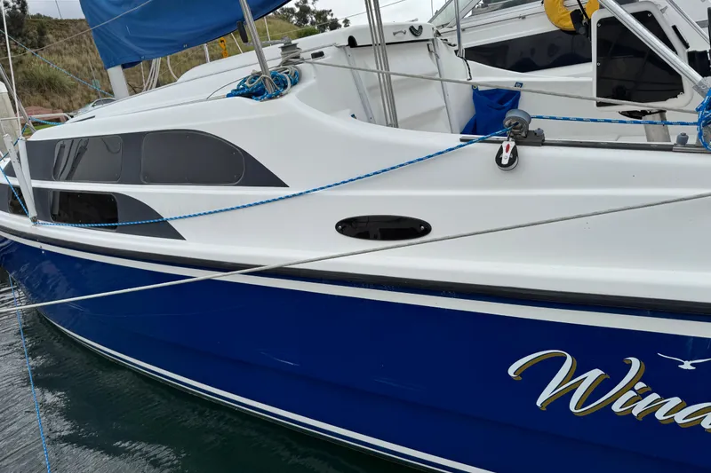 Slide: The Image of 2005 MacGregor 26M Powersailer with blue hull docked at marina. - 3